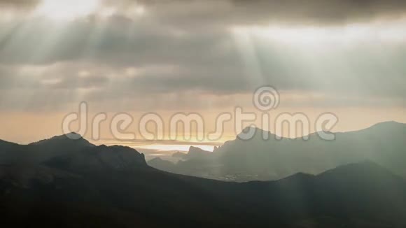 阳光透过云层飘过高山和大海视频的预览图