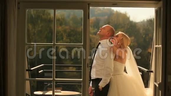 温柔的爱的时刻新娘和英俊的新郎蜜月时拥抱在阳台上视频的预览图