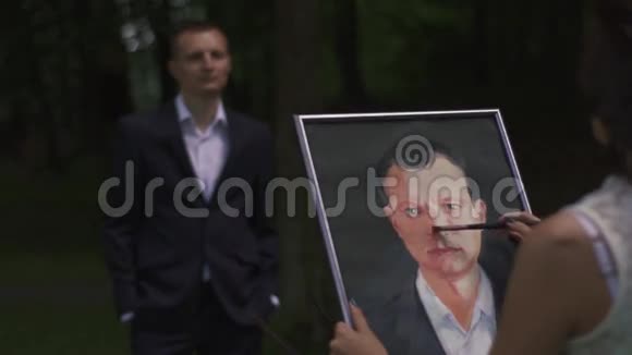 年轻女艺术家在森林里户外画丈夫肖像的后景视频的预览图