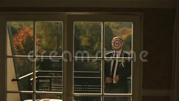 英俊的新郎在豪华酒店客房公寓的阳台上摆姿势视频的预览图