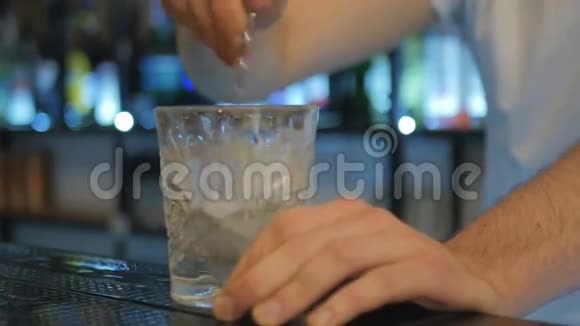 特写镜头酒保把冰和勺子混合在酒吧里视频的预览图