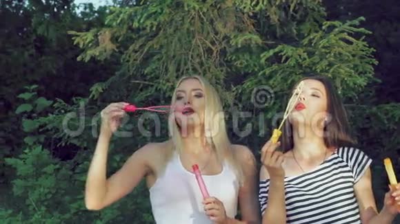 快乐的女孩在夏天的公园里吹着五颜六色的肥皂泡慢慢地视频的预览图