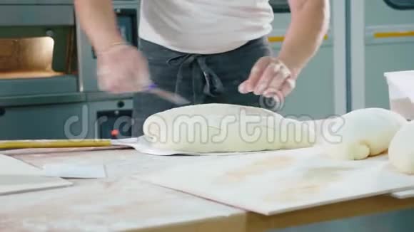 专业面包师把生面包放到商业厨房的烤箱里视频的预览图