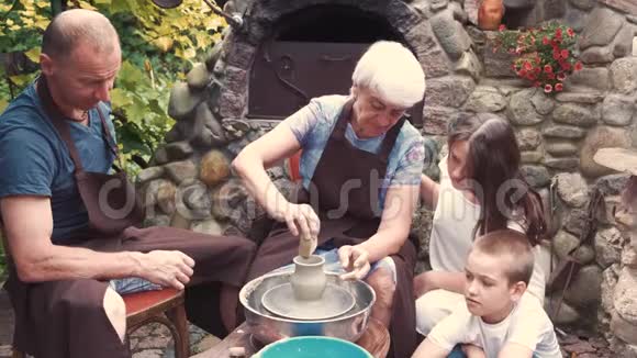 带着孙子孙女的祖父母用陶器制作水壶视频的预览图