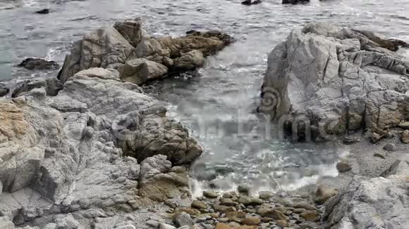 海滩上的岩石之间的波浪起伏视频的预览图