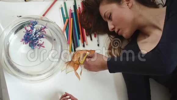 美丽的年轻女孩艺术家画金鱼靠近顶部的景色视频的预览图