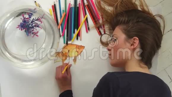 美丽的女艺术家把金色的鱼画在最高的视野上视频的预览图