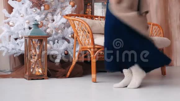 穿着连衣裙的年轻女子在圣诞树附近跳跃和跳舞视频的预览图