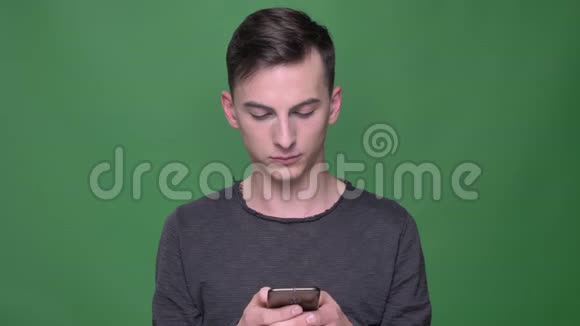 年轻英俊的白种人男性的特写镜头使用绿色背景的手机视频的预览图