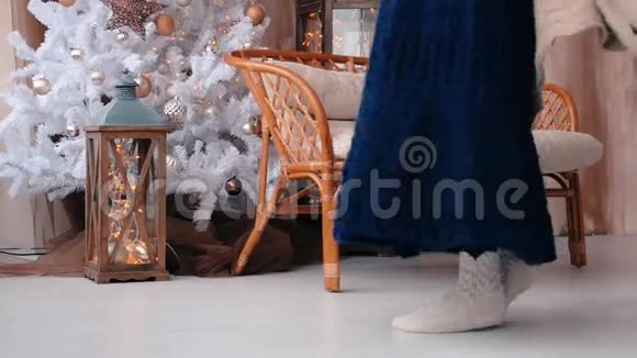 穿着连衣裙的年轻女孩在圣诞树附近跳跃和跳舞视频的预览图