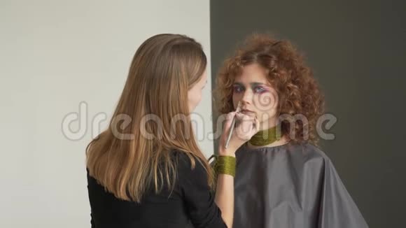 专业化妆师将色调粉涂于长卷发蓝眼睑金发模特视频的预览图