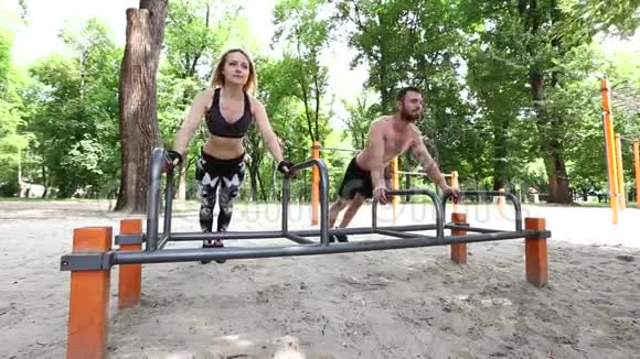 在公园里做俯卧撑运动的年轻女子和留胡子的男人视频的预览图