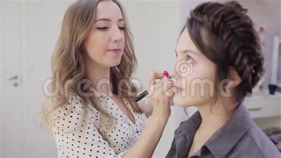 美丽的黑发女孩使用专业化妆师的服务美容店化妆师和她的客户视频的预览图