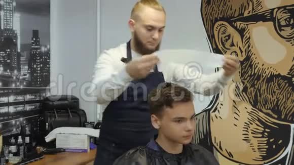 男士美容师理发店一个年轻人从一个留着胡子的男人那里得到理发和理发服务视频的预览图