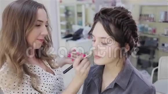 美丽的黑发女孩使用专业化妆师的服务美容店化妆师和她的客户视频的预览图