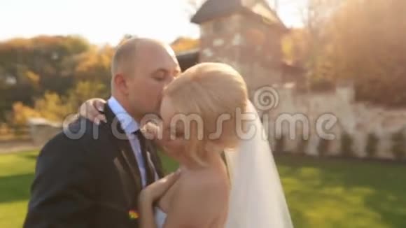 新婚快乐的新婚夫妇在中世纪城堡的院子里轻轻地接吻视频的预览图