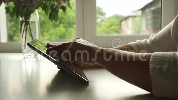 侧视图家中使用数字平板电脑的老年妇女的手视频的预览图