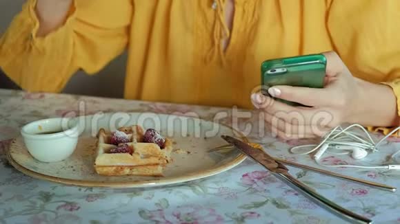 美女正在咖啡馆吃华夫饼用智能手机拍照视频的预览图