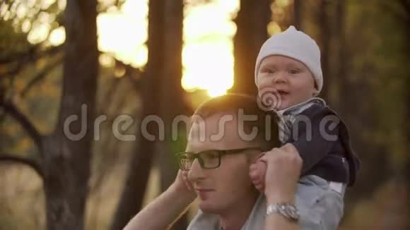 一家三口的镜头在公园里合拍父亲把儿子抱在肩上幸福家庭视频的预览图