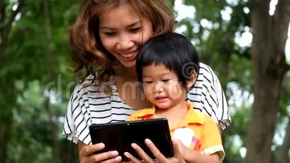 一个亚洲男孩和母亲正在平板电脑上玩有趣的游戏视频的预览图