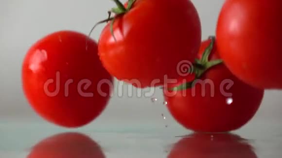 红色成熟的西红柿在潮湿的玻璃表面溅落和反弹慢动作视频的预览图