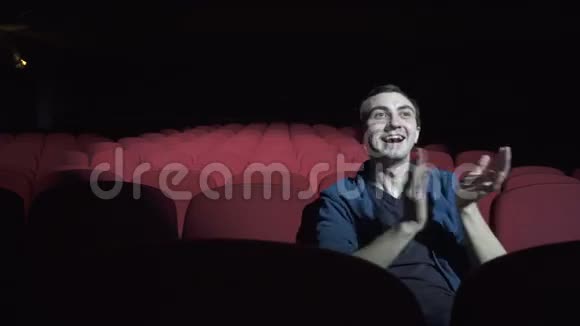 在黑暗的电影院里坐在舒适的红色椅子上鼓掌视频的预览图