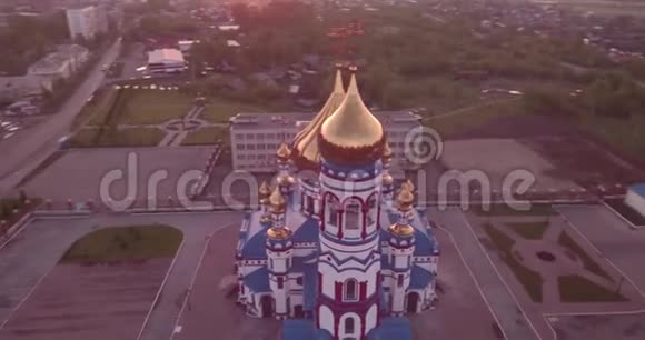 空中飞行在小镇的新教堂周围基督教圣殿和金色教堂穹顶在黎明4K视频的预览图