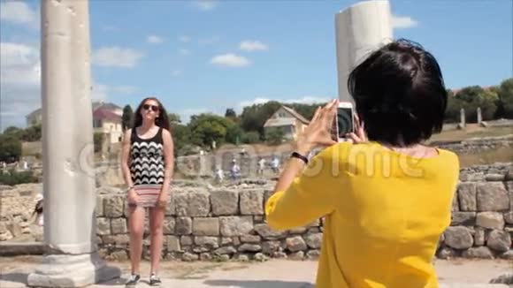 幸福的女人在古城遗址背景上用智能手机拍照女朋友视频的预览图