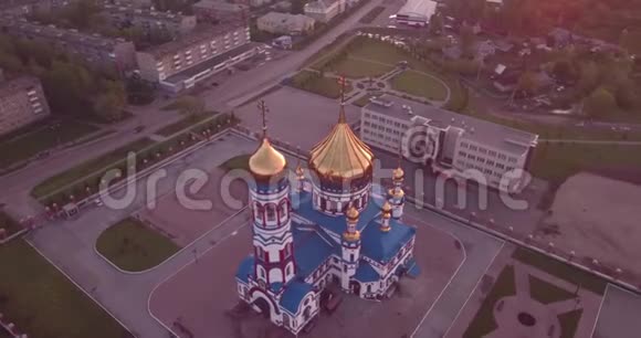 空中飞行在小镇的新教堂周围基督教圣殿和金色教堂穹顶在黎明4K视频的预览图