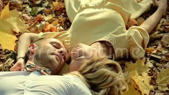 微笑的夫妇躺在秋天的公园里视频的预览图