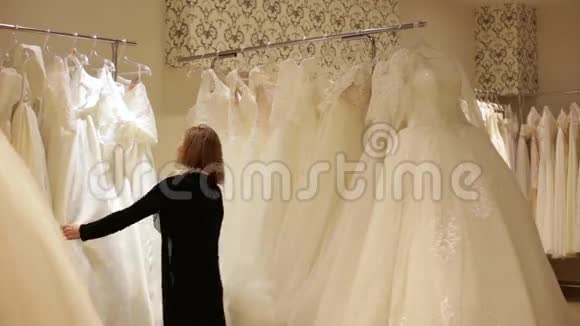 年轻漂亮的女人在婚礼店里挑选白色礼服Wed概念视频的预览图