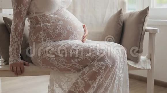 孕妇坐在靠窗的椅子上摸着她的肚子看着远处视频的预览图