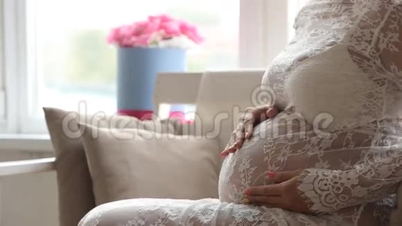 孕妇坐在靠窗的椅子上摸着她的肚子看着远处视频的预览图