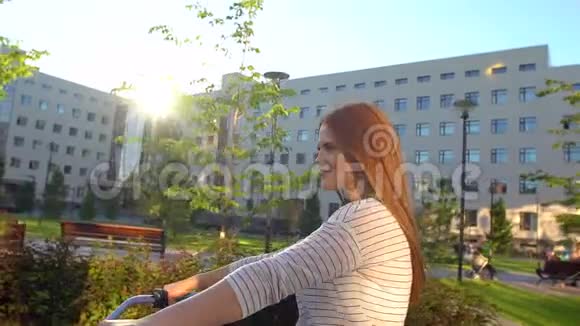 年轻快乐浪漫的女人在夏天的户外快乐地骑自行车穿过阳光明媚的街道年轻女孩骑自行车视频的预览图