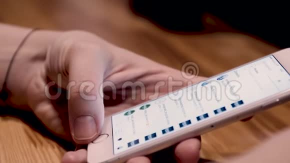 特写女性手握和使用智能手机阅读新闻饲料晚上在咖啡馆与bokeh背景视频的预览图