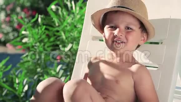 喝橙汁的男孩在海滩上戴帽子的男孩视频的预览图
