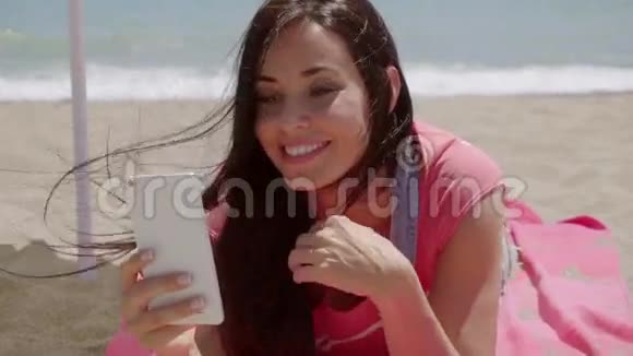 在海滩上用电话笑女人视频的预览图