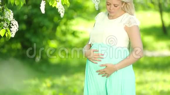花园里一个金发的孕妇的肖像视频的预览图