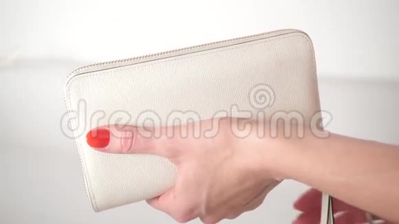 穿着红色指甲油的女孩打开了她的白色钱包视频的预览图
