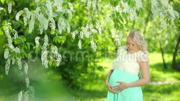 花园里一个金发的孕妇的肖像视频的预览图
