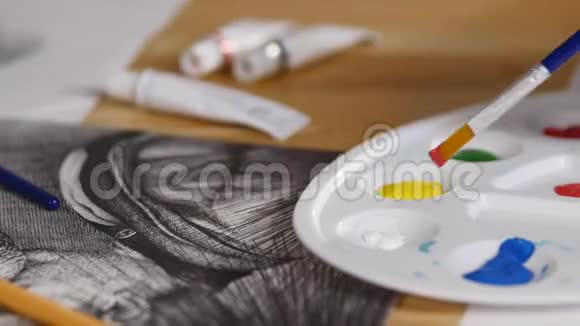 妇女手中的画笔特写将颜料混合在调色板上视频的预览图