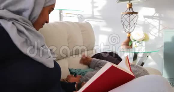 年轻的母亲在客厅看书视频的预览图