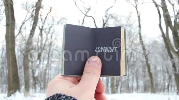 冒险手拿一本书背景是白雪皑皑的冬季公园视频的预览图