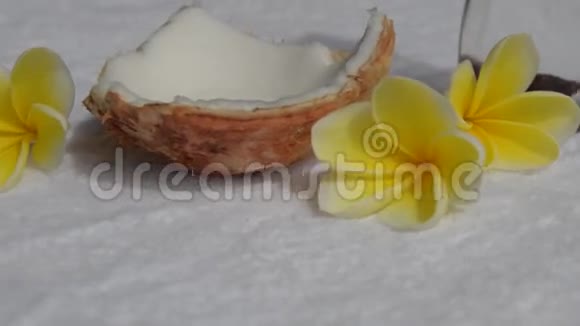 白色毛巾上的鲜花椰子和椰子按摩油视频的预览图