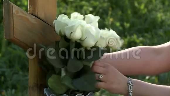 女人把白玫瑰放在木制墓碑上视频的预览图
