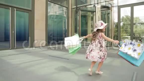 可爱的小女孩带着购物袋走出商店视频的预览图