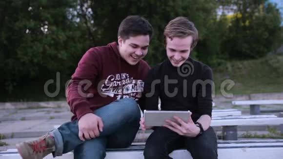 两个带平板电脑的男性朋友在户外聊天冲浪视频的预览图