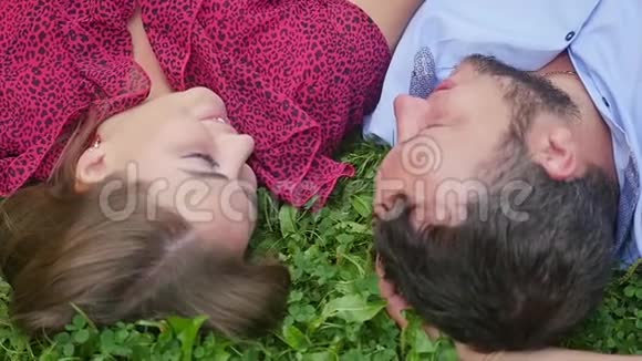 幸福的一对夫妇在绿草上的公园里休息慢动作微笑的男人和女人交谈享受温暖的夏日视频的预览图