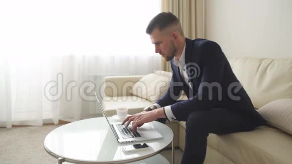 年轻成功的帅哥在酒店房间里用电脑工作视频的预览图