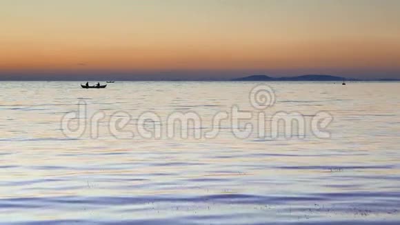 夕阳西下渔人的船浮在平静的水面上4k视频的预览图